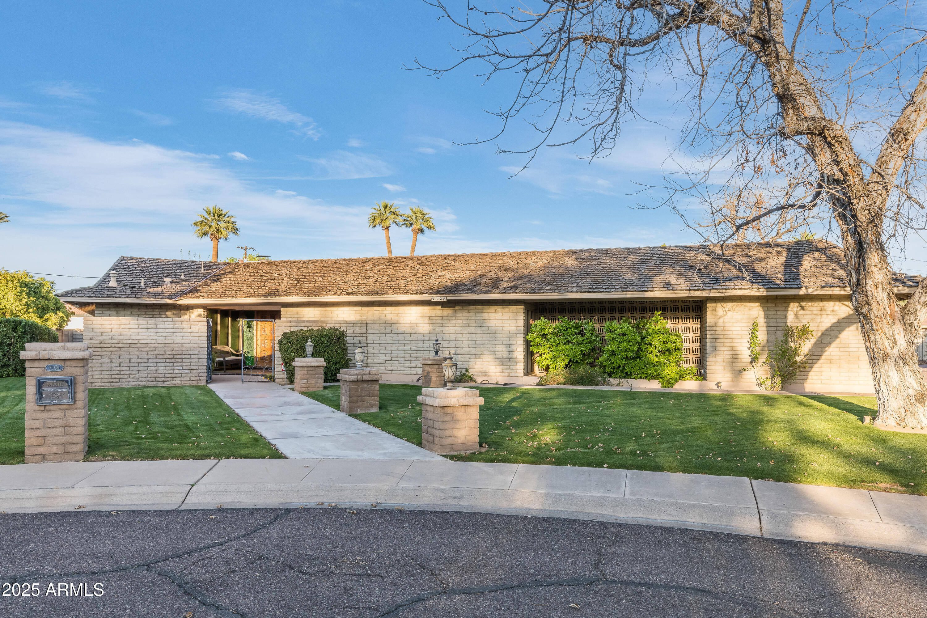 a front view of a house with a yard and potted plants