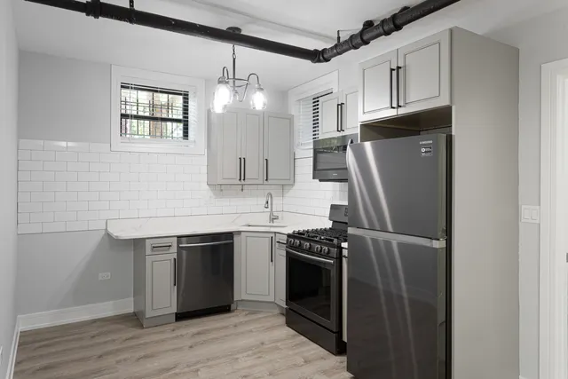 a kitchen with stainless steel appliances granite countertop a refrigerator a sink dishwasher a stove and white countertops with wooden floor