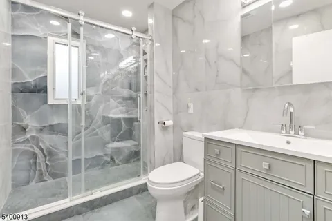 a bathroom with a shower sink vanity mirror and toilet