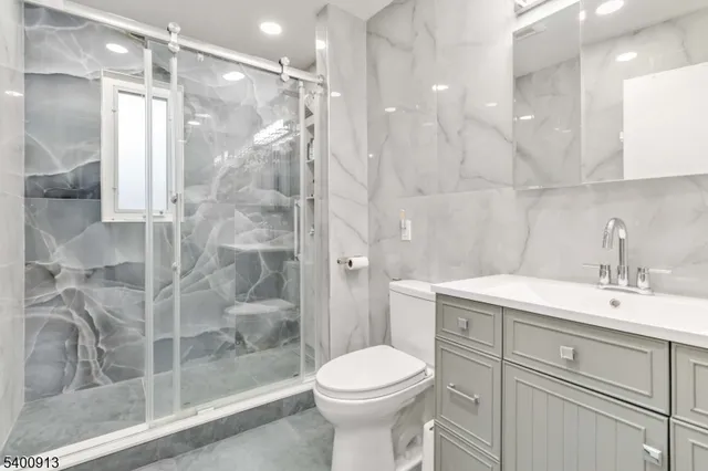 a bathroom with a shower sink vanity mirror and toilet