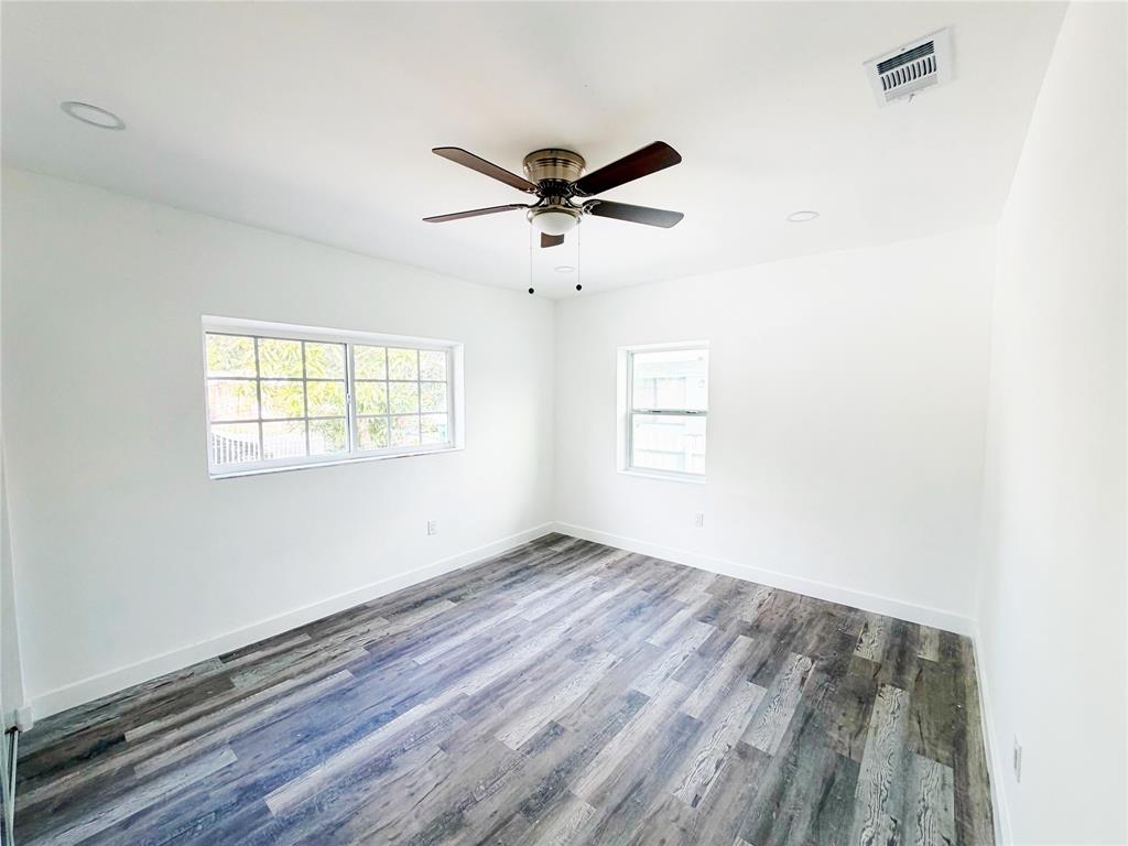 778 Northwest 80th Street Miami, FL 33150 - Photo 11 of 35 an empty room with wooden floor ceiling fan and windows