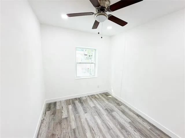 an empty room with a window and a ceiling fan