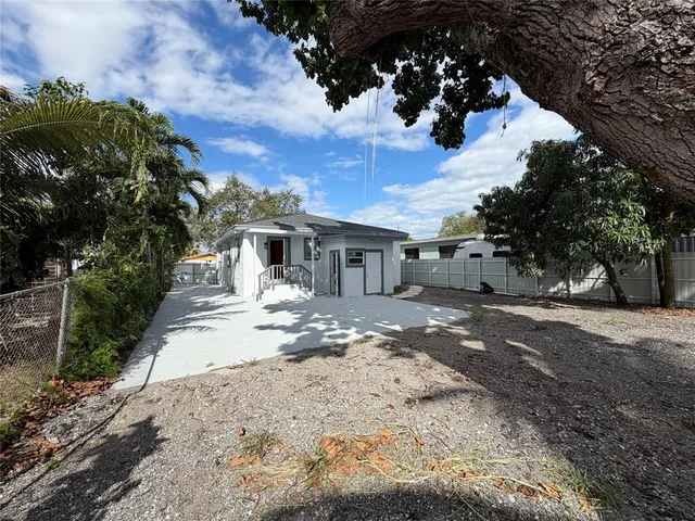 a front view of a house with a dirt yard and a large tree