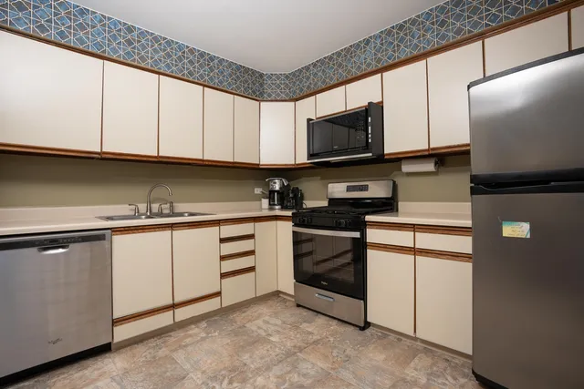 a kitchen with stainless steel appliances granite countertop a stove a sink and a microwave