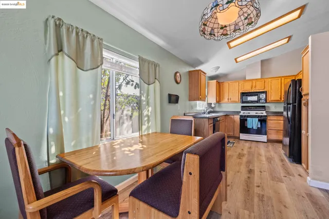 a kitchen with stainless steel appliances granite countertop a sink a stove a dining table and chairs