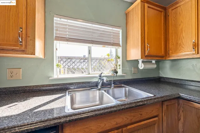 a kitchen with granite countertop a sink a window and cabinets
