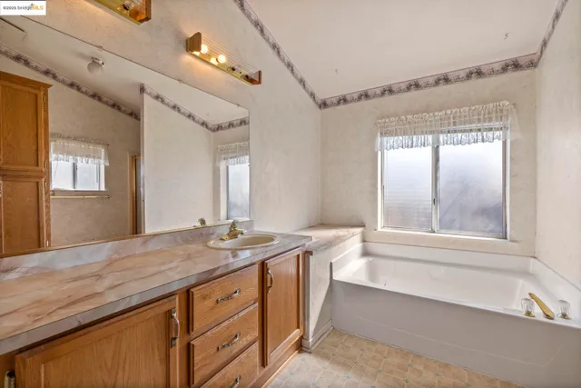 a bathroom with a granite countertop sink mirror and a bathtub