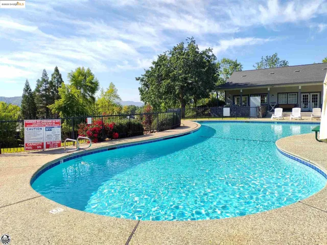 a view of a swimming pool with lawn chairs and a fire pit