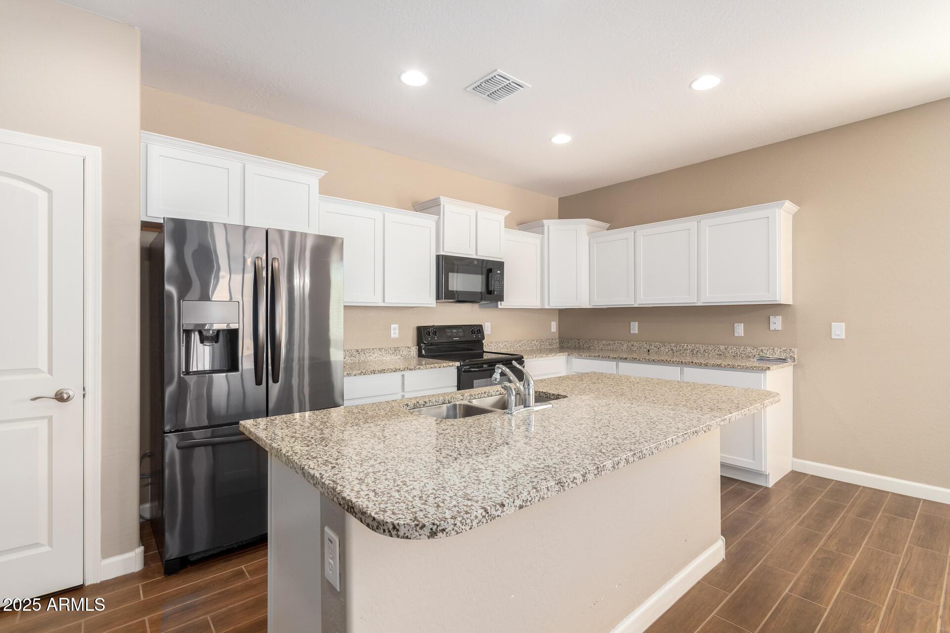 23882 West Ripple Road Buckeye, AZ 85326 - Photo 9 of 26 a kitchen with kitchen island granite countertop a sink stove and refrigerator