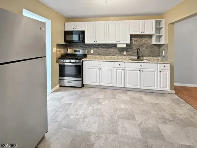 a kitchen with granite countertop a refrigerator and a stove top oven