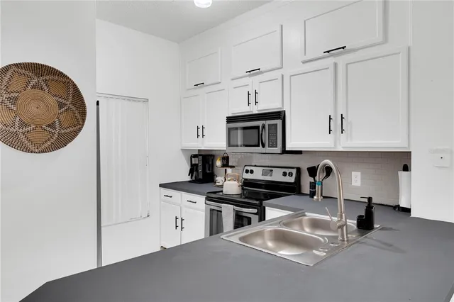 a kitchen with stainless steel appliances granite countertop a sink stove top oven and cabinets