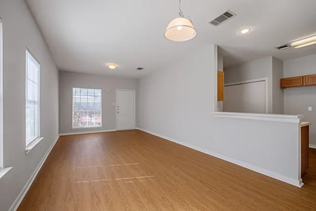 an empty room with wooden floor and windows