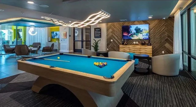 a room with furniture pool table flat screen tv and windows