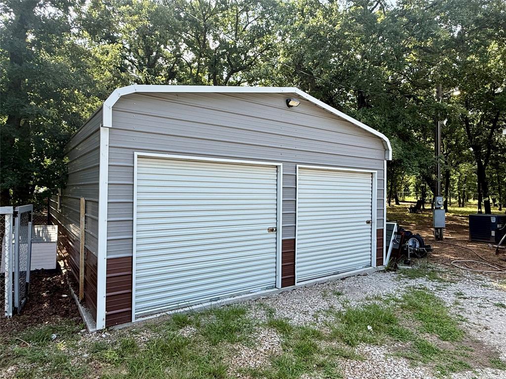 145 Adalida Lane Springtown, TX 76082 - Photo 26 of 29 Two-bay metal outbuilding with corrugated siding and two roll-up doors, set on a concrete slab