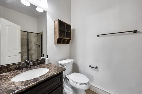 a bathroom with a granite countertop sink toilet and mirror