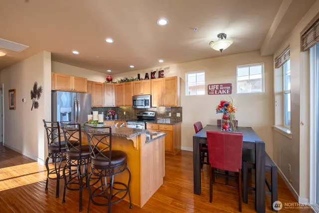 a kitchen with stainless steel appliances kitchen island granite countertop a dining table chairs and refrigerator