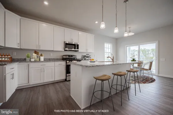 a kitchen with stainless steel appliances granite countertop a stove a sink a microwave a dining table and chairs with wooden floor