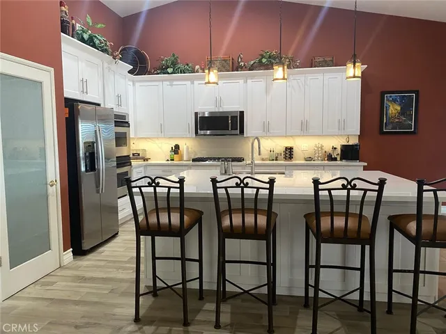 a kitchen with stainless steel appliances a table chairs microwave and refrigerator