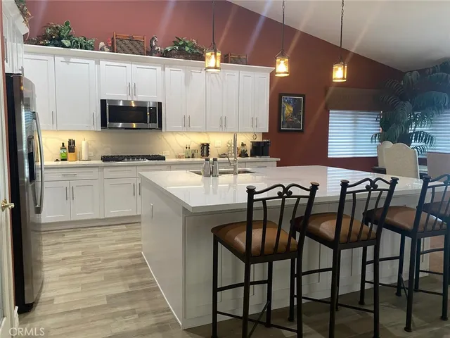 a kitchen with stainless steel appliances a table chairs microwave and refrigerator
