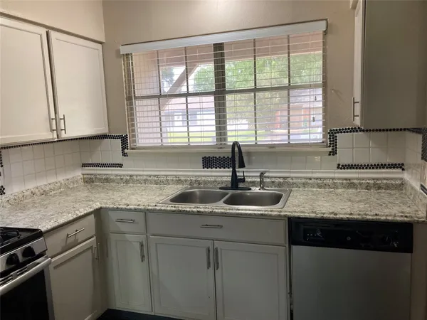 a kitchen with granite countertop white cabinets and a sink