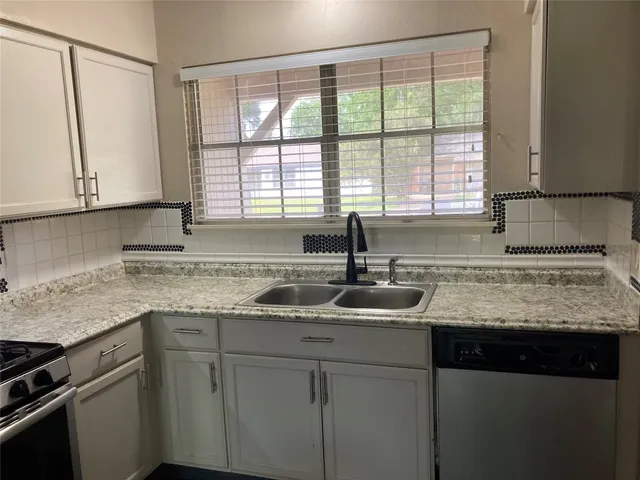 a kitchen with granite countertop white cabinets and a sink