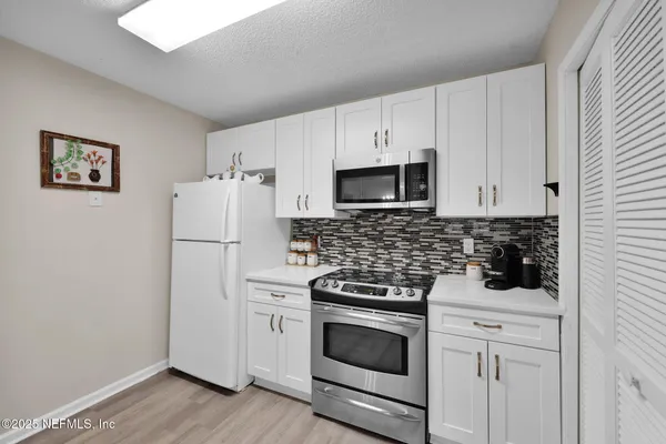 a kitchen with white cabinets and white appliances