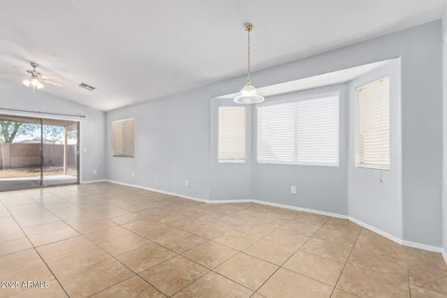 a view of an empty room with window and chandelier fan