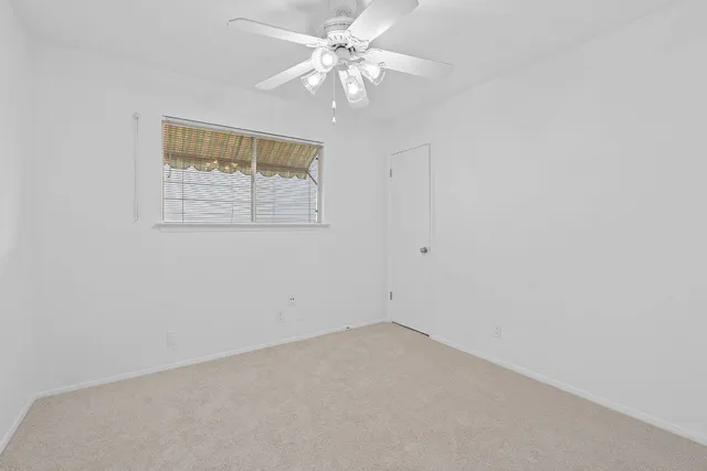 an empty room with a window and a ceiling fan
