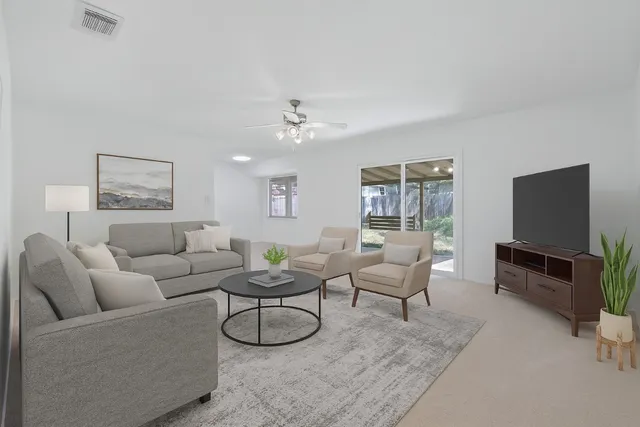 a living room with furniture a flat screen tv and a large window