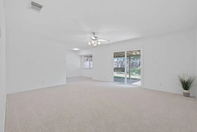 an empty room with windows and chandelier fan