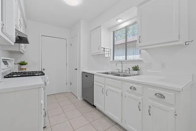 a kitchen with white cabinets and sink