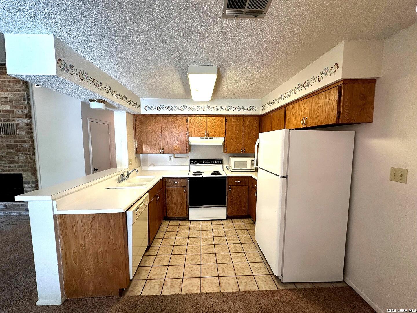 62 Oak Villa Road, Unit F2 Canyon Lake, TX 78133 - Photo 6 of 19 a kitchen with a refrigerator sink and wooden cabinets