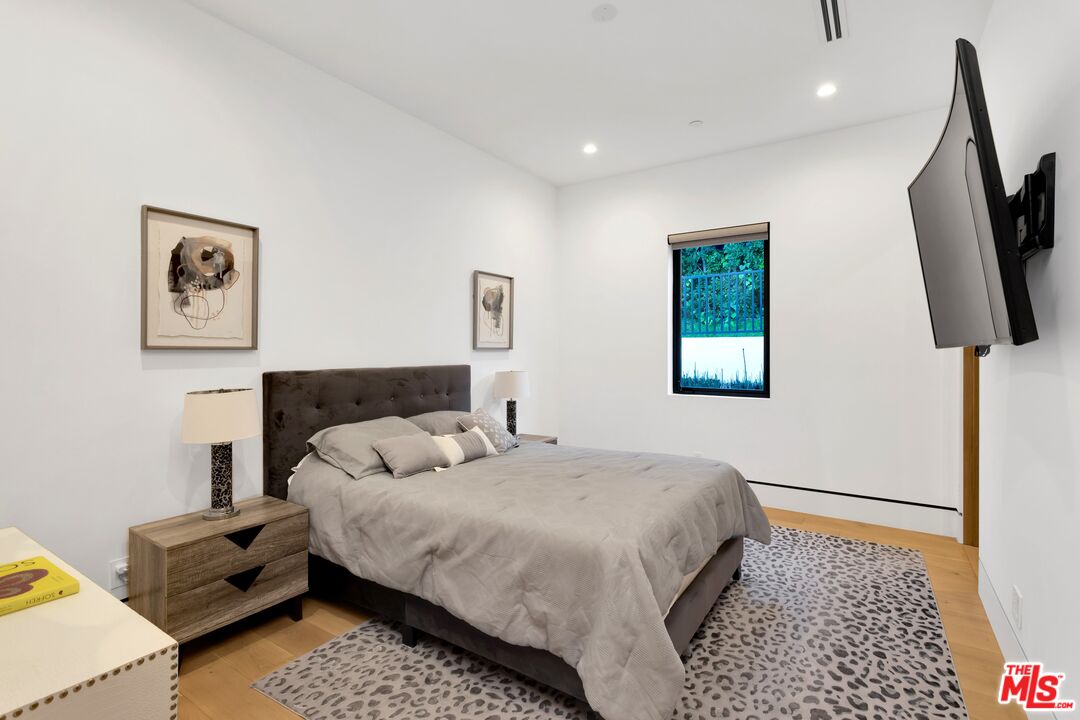 16366 Sloan Drive Los Angeles, CA 90049 - Photo 27 of 54 a bedroom with a bed a painting on the wall and a rug