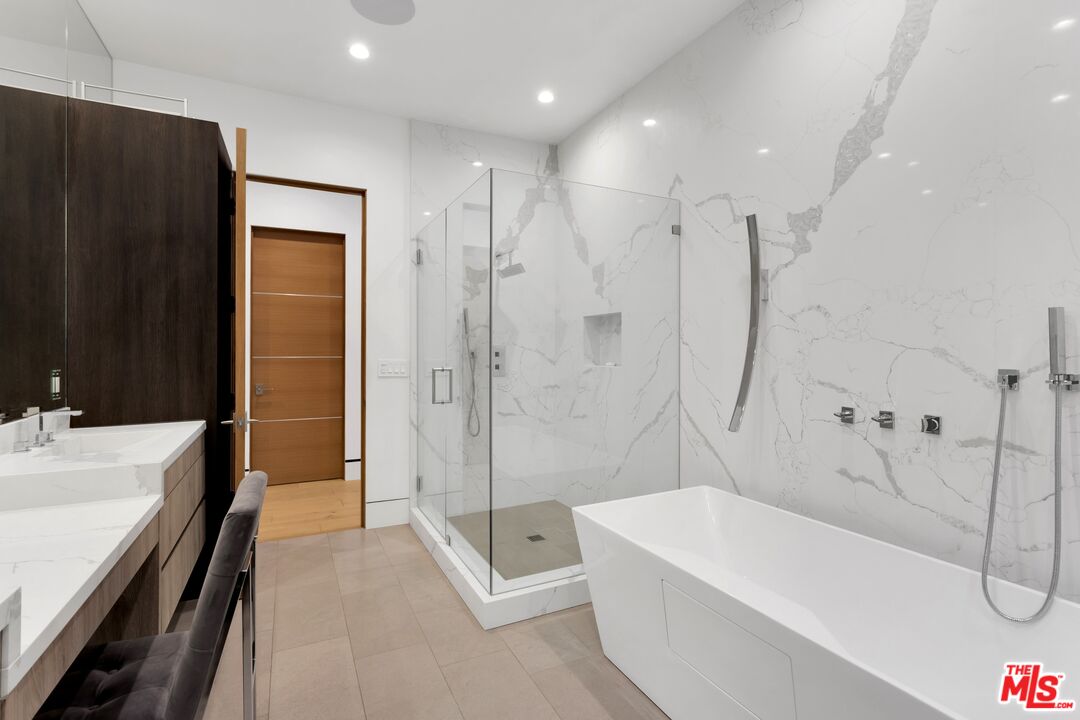 16366 Sloan Drive Los Angeles, CA 90049 - Photo 35 of 54 a bathroom with a tub a sink a mirror and a shower