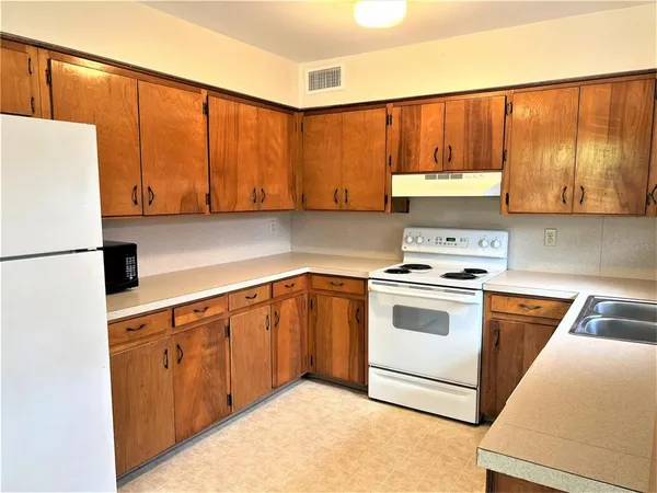 a kitchen with stainless steel appliances granite countertop a stove a sink and a refrigerator with wooden cabinets