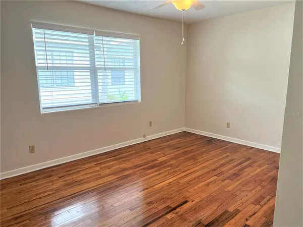 a view of empty room with wooden floor and fan