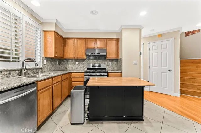 a kitchen with stainless steel appliances granite countertop wooden cabinets a sink and a counter top space