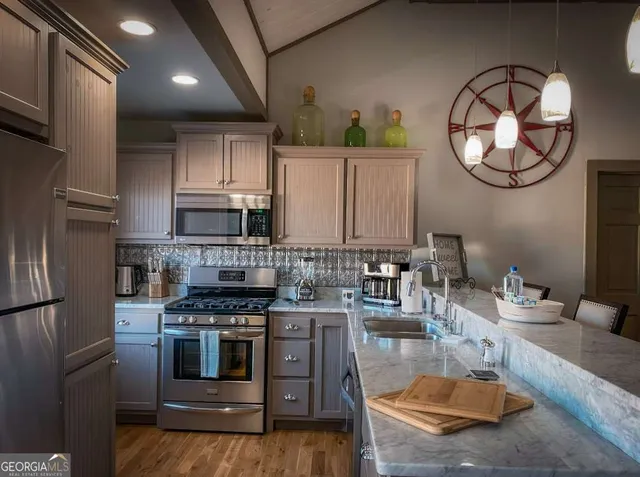 a kitchen with stainless steel appliances granite countertop a stove a sink dishwasher and a refrigerator with wooden floor