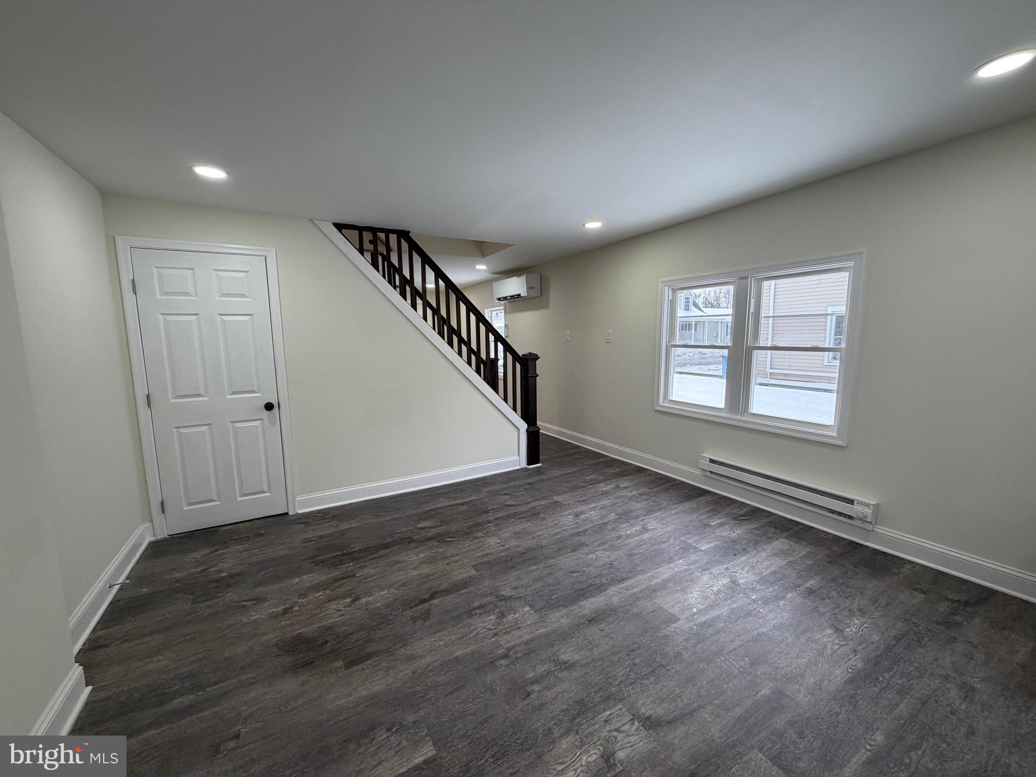 197 Main Street Hartly, DE 19953 - Photo 5 of 17 an empty room with wooden floor staircase and windows