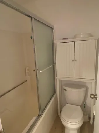 a white toilet sitting next to a shower