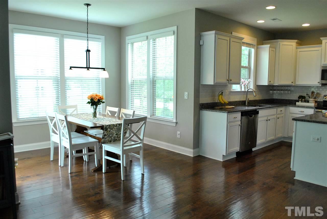 100 Maraketch Court Raleigh, NC 27603 - Photo 14 of 22 a kitchen with stainless steel appliances granite countertop wooden floor dining table and chairs