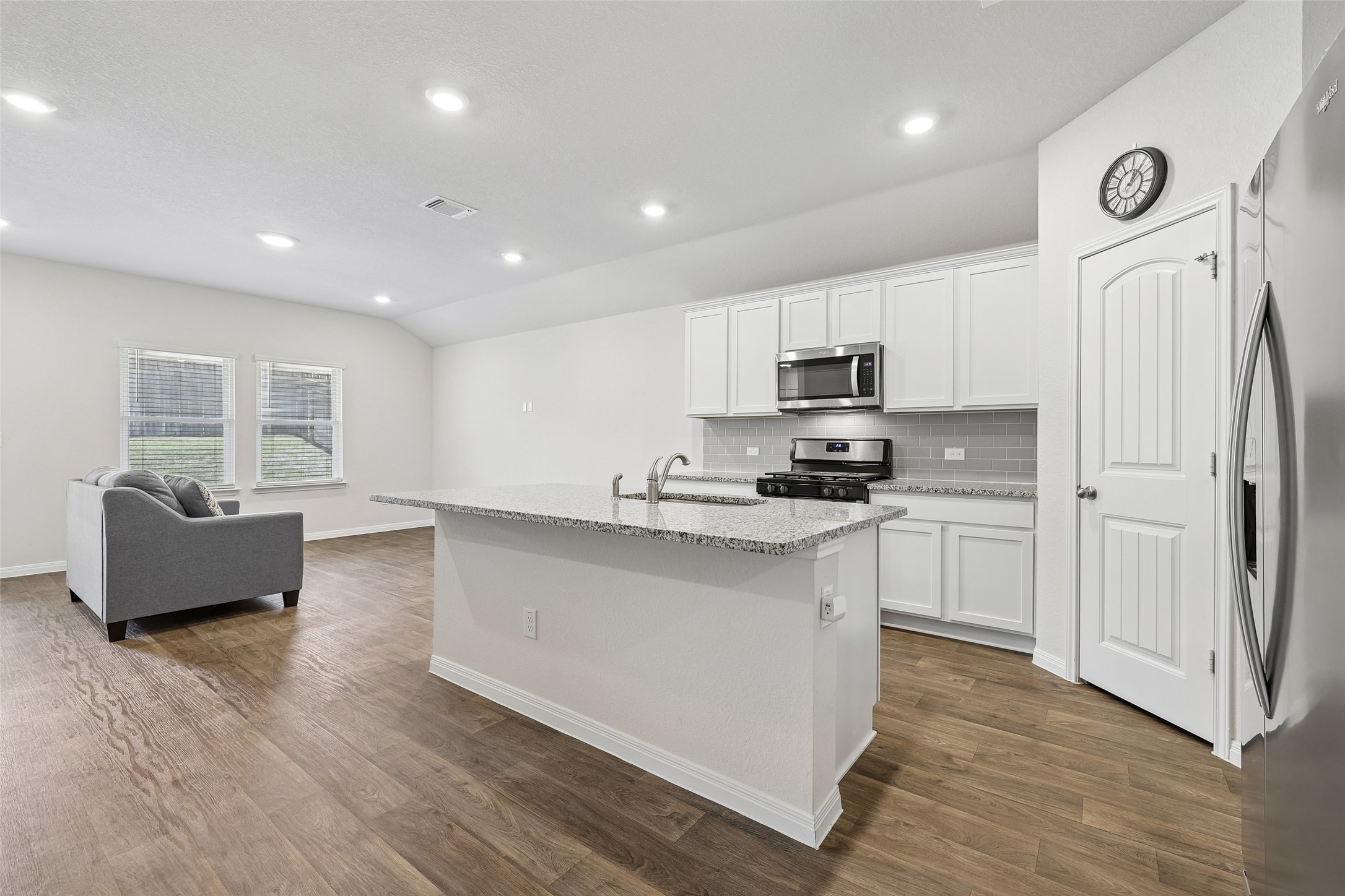 19805 Abigail Fillmore Road Manor, TX 78653 - Photo 10 of 40 A well-lit open-concept space features a modern kitchen island and elegant wood flooring.