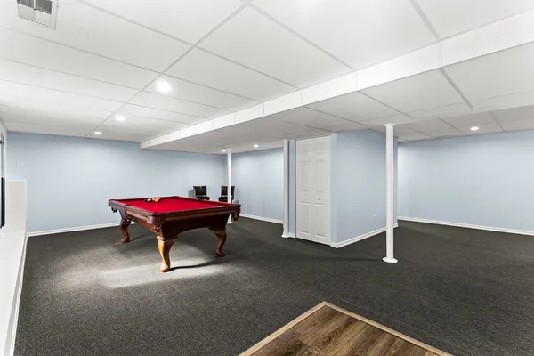 a room with pool table windows and couch