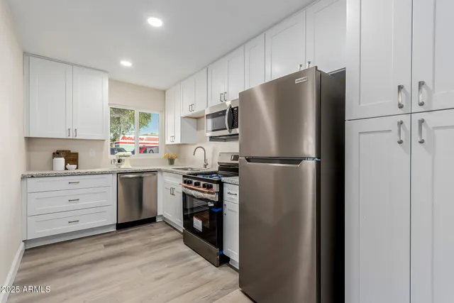 a kitchen with a refrigerator stove and white cabinets