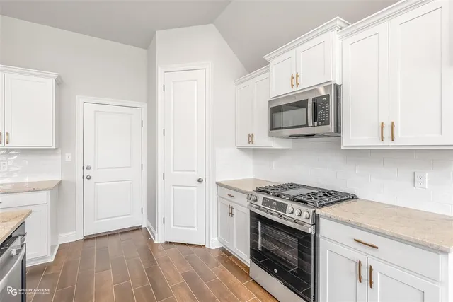 a kitchen with stainless steel appliances white cabinets and a stove top oven