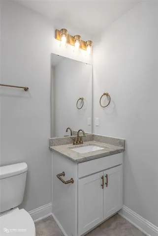 a bathroom with a granite countertop toilet sink and mirror