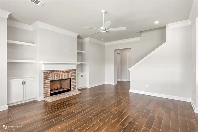 a view of an empty room with wooden floor fireplace and a window
