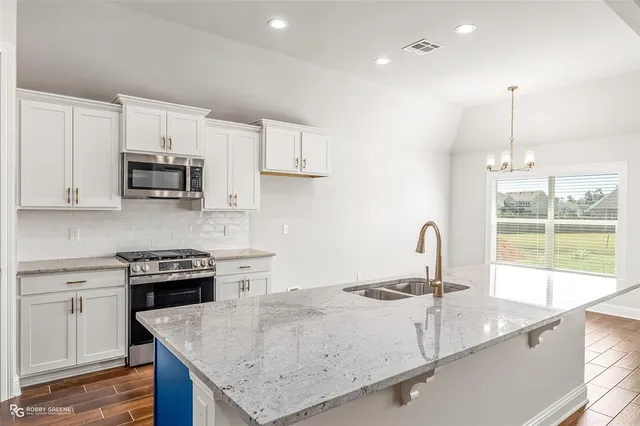 a kitchen with granite countertop a sink a stove and a wooden floor