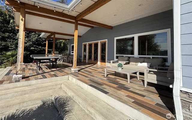 a view of a patio with dining table and chairs with floor to ceiling window and wooden floor