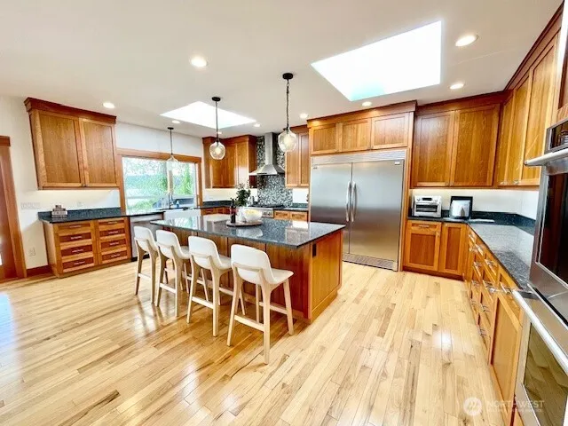 a dining hall with stainless steel appliances granite countertop a stove top oven a dining table and chairs with wooden floor